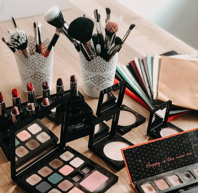 Make-up Pinsel, Lippenstifte und Paletten auf einem Holztisch